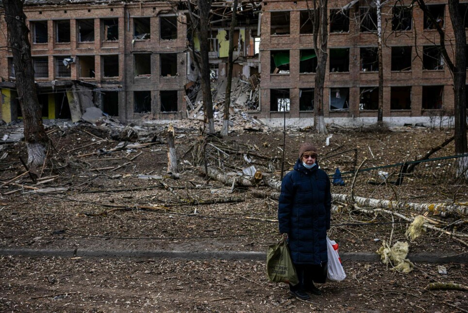 En kvinne står foran en ødelagt bygning etter et russisk missilangrep i byen Vasylkiv 27. februar 2022.
