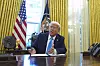 Donald Trump sitter ved skrivebordet i Det ovale kontor og snakker mens han signerer dokumenter.