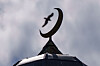 Halvmånesymbol på taket av Islamic Cultural Centre i Oslo mot grå himmel.