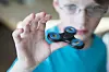 Barn holder en blå og svart fidget spinner nær kameraet.