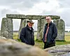Bildet av Phil Harding med langt grått hår og en hatt på hodet, og Matt Leivers med grått hår og briller. Begge har blå jakker og står foran deler av Stonehenge. Himmelen bak er grå.