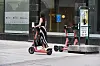En kvinne står på en sparkesykkel i Oslo sentrum. Hun har ikke hjelm på seg og kjører på fortauet.