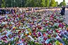 Kongefamilien står ved et stort blomsterhav mens folkemengden samler seg på Slottsplassen.