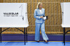 Magdalena Andersson i blå dress ved et svensk valglokale med stemmesedler.