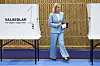 Magdalena Andersson i blå dress ved et svensk valglokale med stemmesedler.