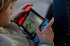 Nærbilde av et barn som spiller på en Nintendo Switch innendørs.