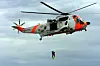 Sea King-helikopter heiser en redningsmann over sjøen under en redningsøvelse.