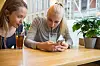 To tenåringsjenter på kafé ser på en mobiltelefon ved siden av glass med iste.