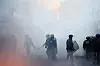 Opprørspoliti står i tett røyk på en gate i Paris etter demonstrasjoner.